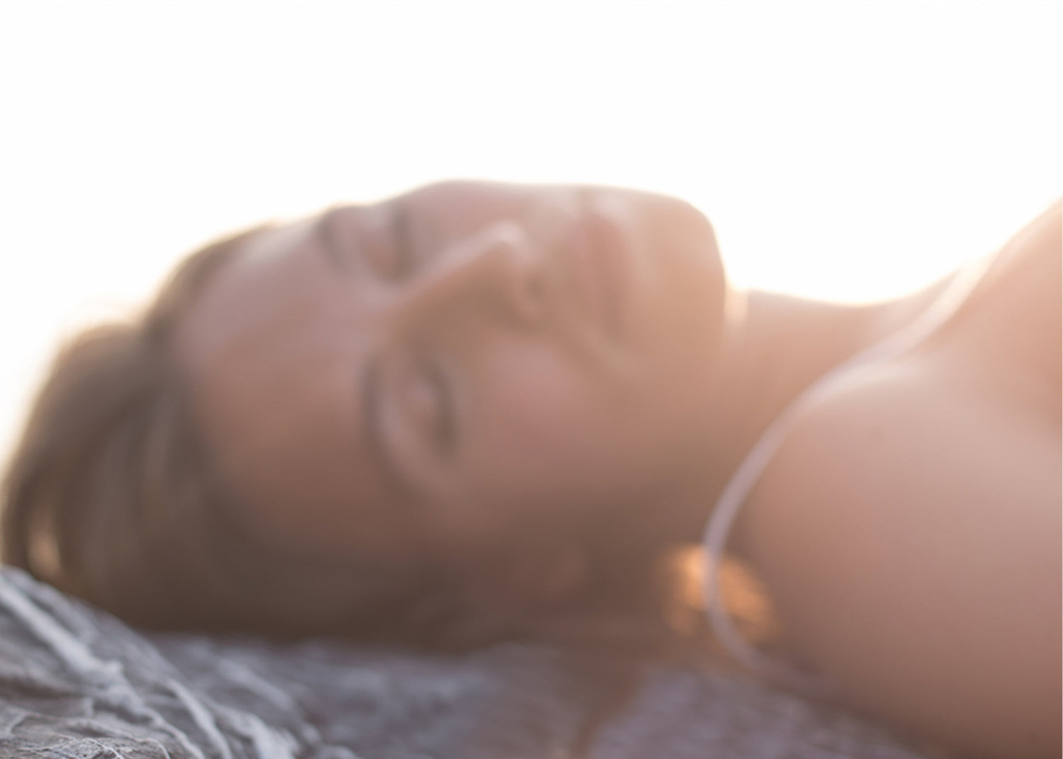 Blurred woman face laying on rocks - image for Kear natural skincare face collection.