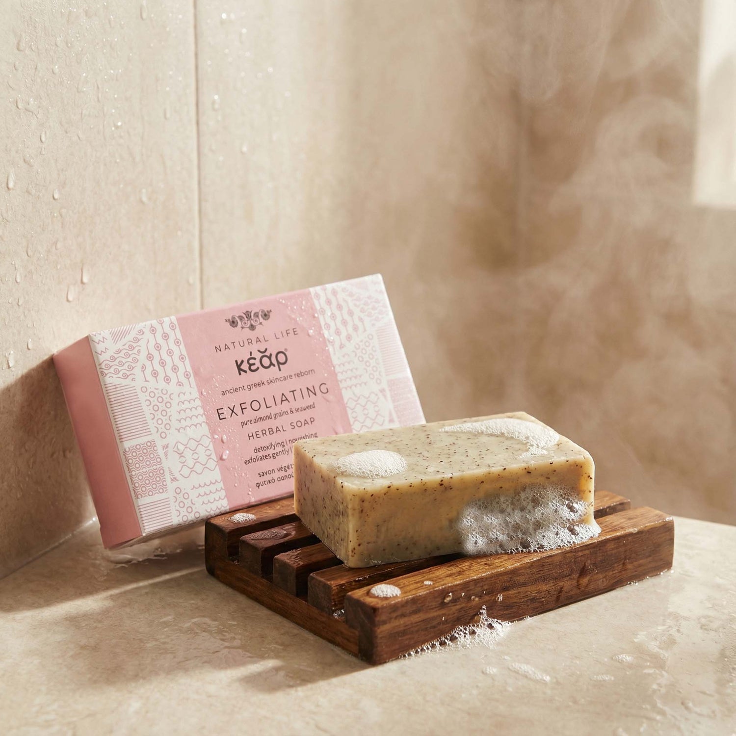 Bar of Kear Exfoliating Herbal Soap on a wooden soap dish with packaging in the background.