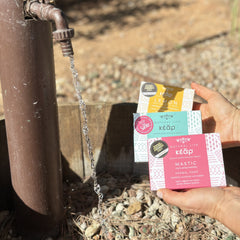 Hands holding three Kear herbal soaps with mastic, chamomile and lemon.